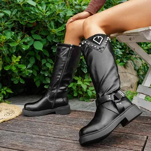 Detailansicht schwarzer Lederstiefel mit silbernen Nieten und herzförmigem Metallausschnitt.