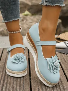 Detalle en primer plano de zapatos de plataforma azul claro con flor 3D y suela de cuerda