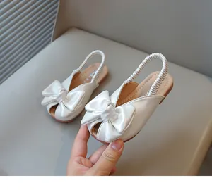 Detail view of white girls' sandals with a large decorative bow and peep-toe.