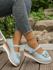 Elegantes zapatos de cuña Mary Jane azul claro con detalle floral en deck de madera