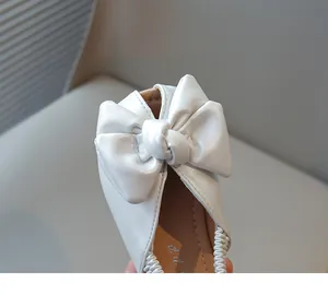 Close-up of elegant white girl's princess shoe featuring a large decorative bow detail
