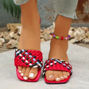 Detailed macro view of the vibrant braided strap on red square-toe flat sandals.