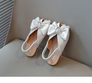 Close-up of white girls' bow sandals with braided elastic slingback strap
