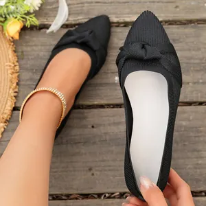 Primo piano di ballerine a punta in maglia nera traspirante con un elegante fiocco decorativo