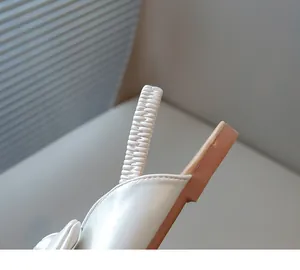 Detailed macro view showing elastic heel strap and neat stitching on girls white sandal