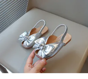 Macro view of stylish silver girls sandals featuring a large bow and elastic strap detail