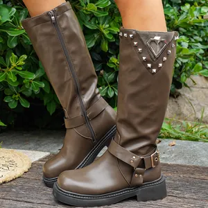 Detailansicht brauner Retro-Ritterstiefel mit Gürtelschnalle und metallener Herzverzierung.