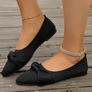 Ballerine in maglia traspirante nere con fiocco su sfondo di ponte in legno