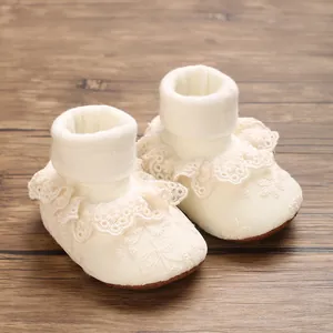 Detailed view of cream lace newborn baby girl socks with soft knit cuffs and ruffles.