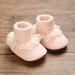 Detailed view of pink baby booties with delicate lace trim and soft ribbed cotton collar.