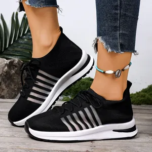 Κοντινό πλάνο κομψών μαύρων fly-knit sneakers με λευκές σόλες πλατφόρμας και ρίγες.