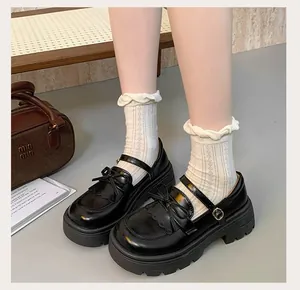 Detailed shot of black Mary Jane shoes featuring chunky platform soles and bow decorations.
