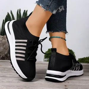 Κοντινή λήψη μαύρων πλεκτών sneakers με πλατφόρμα φορεμένα με ξεφτισμένο τζιν παντελόνι.
