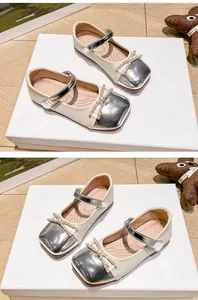 Primer plano de zapatos Mary Jane para niña con lazo de perlas y puntera plateada