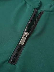 Detail of silver zipper puller on a dark green men's athletic half-zip sweatshirt