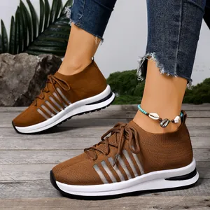 Λεπτομέρεια από καφέ πλεκτά παπούτσια fly-knit με σόλα πλατφόρμα και κορδόνια.