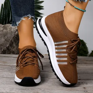 Κοντινό πλάνο καφέ αναπνεύσιμων sneakers flyknit με χοντρές λευκές σόλες πλατφόρμας.