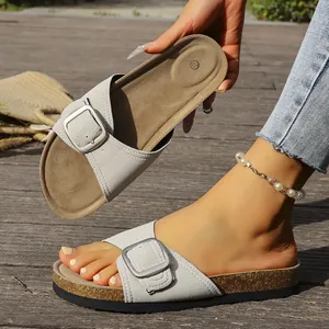 Détail de sandales à boucles grises avec semelle en liège et chaîne de cheville
