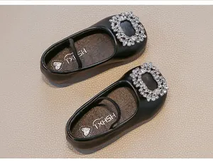 Detailed view of girls' black leather Mary Jane shoes featuring a shiny rhinestone buckle