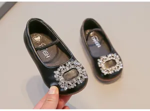 Close-up view of the sparkling crystal buckle on a toddler girl's elegant black leather flat.