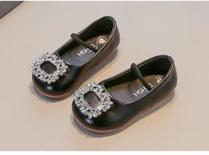 Detailed view of girls' black leather ballet flats with sparkling rhinestone buckles.