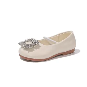 Detailed side view of cream girl's leather flats featuring a sparkling rhinestone buckle