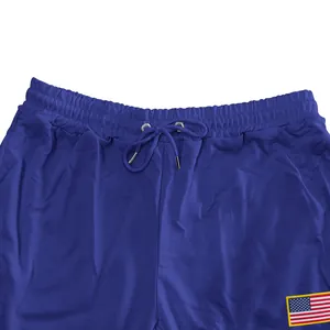 Detail van blauwe heren joggingbroek met trekkoord en Amerikaanse vlag patch