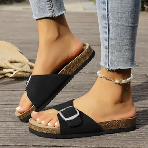 Détail de sandales noires à boucle style Birkenstock sur terrasse bois