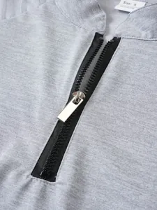 Detailed macro view of the metal zipper and grey knit fabric on men's sports sweatshirt.