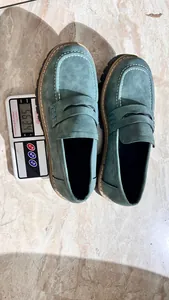Green chunky loafers weighed on digital scale showing product mass