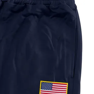 Detail van een marineblauwe sportbroek met een Amerikaanse vlag patch en handige zijzak