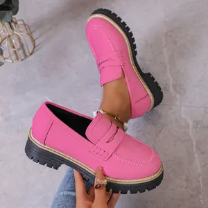 Detailed view of pink chunky platform loafers with black lug soles and white stitching