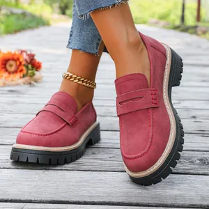 Detailed macro shot of stylish red platform loafers with thick soles worn outdoors