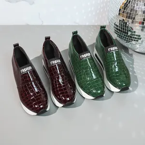 Dettaglio scarpe da ginnastica plateau con stampa coccodrillo bordeaux e verde scuro