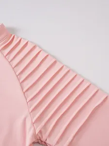 Detailed macro view of the pleated shoulder texture on a pink men's fitness sweatshirt