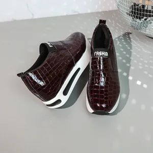 Dettaglio ravvicinato di sneaker platform bordeaux da donna con stampa coccodrillo lucida
