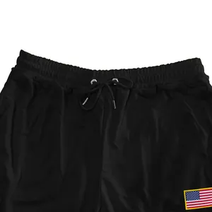 Detailweergave van zwarte joggingbroek in Amerikaanse stijl met trekkoord en VS-vlag patch