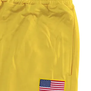 Detail van gele heren joggingbroek met Amerikaanse vlag patch en elastiek band