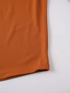 Close-up of the hem stitching on a burnt orange men's athletic sports shirt.