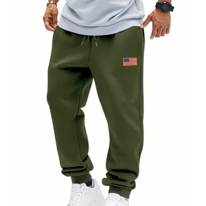 Detail van olijfgroene joggingbroek met een kleine Amerikaanse vlagpatch op de dij van de man.