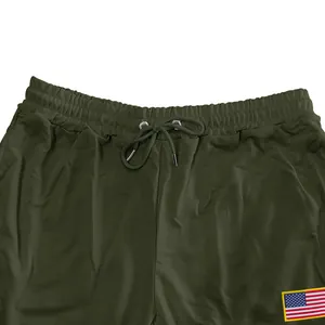 Detail van olijfgroene joggingbroek met trekkoord in de taille en Amerikaanse vlag patch