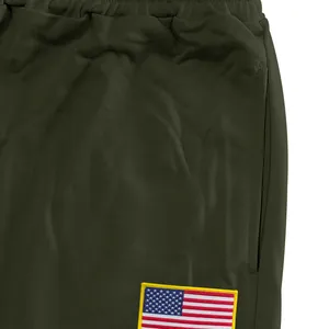 Close-up van een olijfgroene joggingbroek met Amerikaanse vlag-patch detail