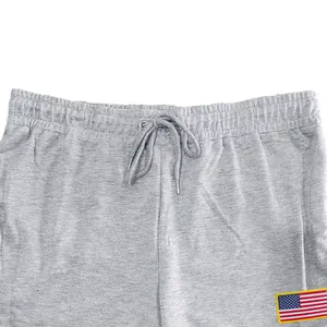 Detail van elastische taille met trekkoord en Amerikaanse vlag patch op grijze joggingbroek
