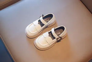 Detail view of cream-white British style girls' leather shoes with wavy edge buckle straps.
