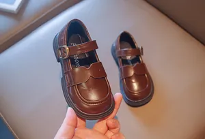 Detailed view of brown girls' British style Mary Jane leather shoes held in hand