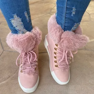 Detail view of fashionable pink fur-trimmed winter snow boots with golden metallic eyelets