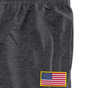 Detailopname van een donkergrijze joggingbroek met een geborduurde Amerikaanse vlag patch