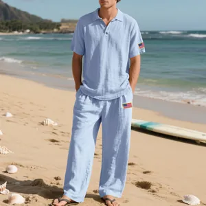 Heren set van lichtblauw linnen shirt en broek met vlag patches gedragen op het strand