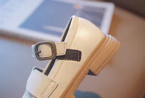 Close-up detail showing the buckle and velcro strap on white girl's Mary Jane shoe