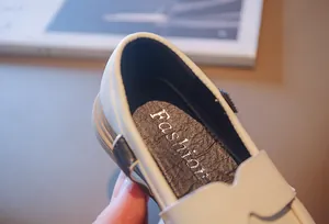 Close-up detail of girls' cream loafers featuring a soft cushioned black insole